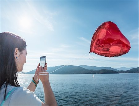 Mature woman photographing heart shaped balloon Stock Photo - Premium Royalty-Free, Code: 614-07240058