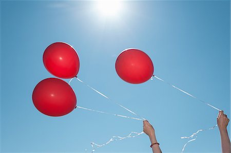 fresh air - Hands holding three red balloons against blue sky Stock Photo - Premium Royalty-Free, Code: 614-07240061