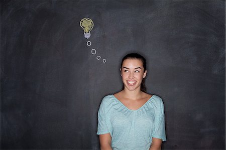 Young woman by blackboard with lightbulb Stock Photo - Premium Royalty-Free, Code: 614-07240135