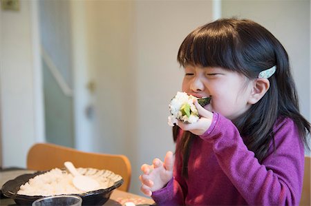 dining rooms in pink - Girl eating large rice parcel at dining table Stock Photo - Premium Royalty-Free, Code: 614-07487166