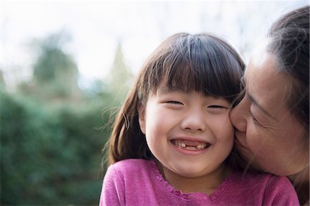 parents - Girl being kissed on the cheek by her mother in the garden Stock Photo - Premium Royalty-Free, Code: 614-07487167