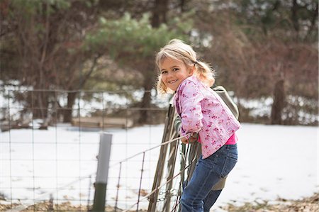 Young girl climbing wire fence in field Stock Photo - Premium Royalty-Free, Code: 614-07587674