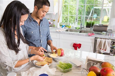 Mid adult couple preparing sandwich at kitchen counter Foto de stock - Sin royalties Premium, Código: 614-07652358