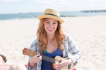 Portrait of young woman on beach playing ukelele Stock Photo - Premium Royalty-Free, Code: 614-07708173