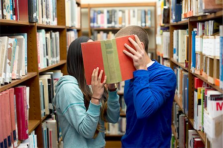 Young couple hiding behind book Stock Photo - Premium Royalty-Free, Code: 614-07708291