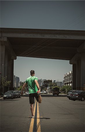 sports city images - Young adult man stretching in road, rear view Stock Photo - Premium Royalty-Free, Code: 614-07735294