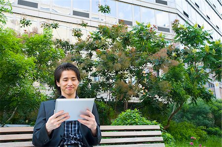 simsearch:649-07560130,k - Mid adult businessman sitting on park bench looking at digital tablet Stock Photo - Premium Royalty-Free, Code: 614-07735446