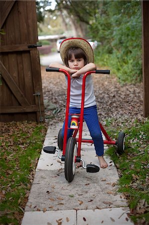 sulky tantrum - Portrait of four year old girl sitting on her tricycle in garden Stock Photo - Premium Royalty-Free, Code: 614-07735498