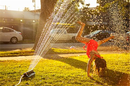 simsearch:614-07768068,k - Girl doing handstand under in garden sprinkler Stock Photo - Premium Royalty-Free, Code: 614-07768090