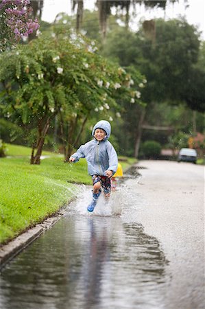 puddle in the rain - Boy in rubber boots running and splashing in rain puddle Stock Photo - Premium Royalty-Free, Code: 614-07805745