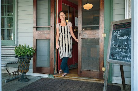 Female shop assistant in doorway of country store Stock Photo - Premium Royalty-Free, Code: 614-07911780
