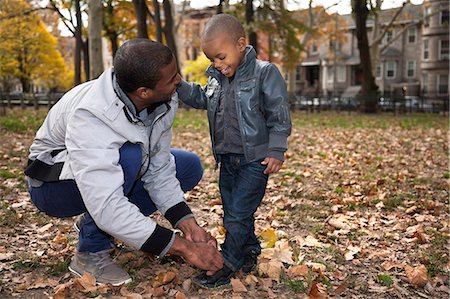 Young man tying toddler sons shoelace in park Foto de stock - Sin royalties Premium, Código: 614-08030484