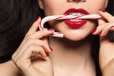 Mid adult woman biting candy cane Stock Photo - Premium Royalty-Free, Code: 614-08030696