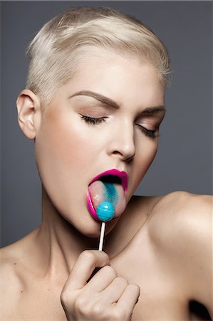 simsearch:614-03982063,k - Young woman licking blue lollipop Photographie de stock - Premium Libres de Droits, Code: 614-08030706