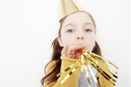 Girl wearing cone party hat blowing streamers Stock Photo - Premium Royalty-Free, Code: 614-08030846