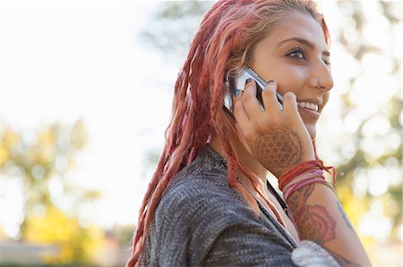 Young woman with pink dreadlocks chatting on smartphone in park Stock Photo - Premium Royalty-Free, Code: 614-08030915