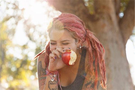 fruit - Young woman with pink dreadlocks giggling whilst eating apple in park Foto de stock - Sin royalties Premium, Código: 614-08030912