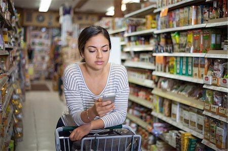 produce grocery store - Young woman shopping with smartphone in health food store Stock Photo - Premium Royalty-Free, Code: 614-08030988