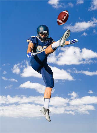 football helmet - American football player jumping and kicking ball Stock Photo - Premium Royalty-Free, Code: 614-08031094