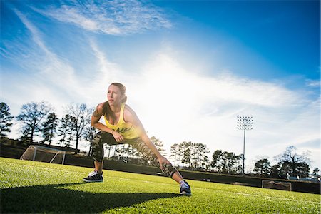 Young female athlete doing stretch exercises on sports field Stock Photo - Premium Royalty-Free, Code: 614-08065923