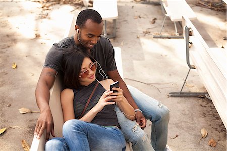 Young couple sitting together, sharing earphones Stock Photo - Premium Royalty-Free, Code: 614-08081286