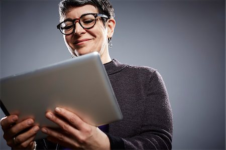 female on gray background - Studio portrait of mature businesswoman reading digital tablet Stock Photo - Premium Royalty-Free, Code: 614-08081363