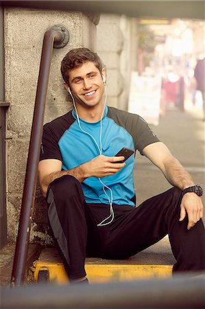 simsearch:693-07672615,k - Portrait of young male runner sitting on city step listening to earphones Stock Photo - Premium Royalty-Free, Code: 614-08081452