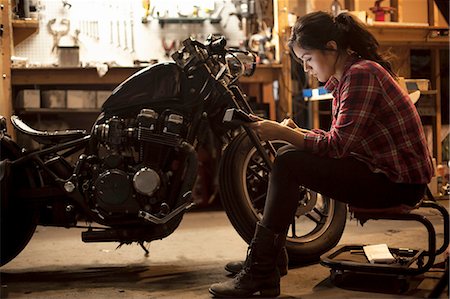 Female mechanic working on motorcycle in workshop Stock Photo - Premium Royalty-Free, Code: 614-08126573