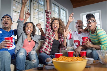 Five adult friends celebrating whilst watching TV from sofa Stock Photo - Premium Royalty-Free, Code: 614-08126613