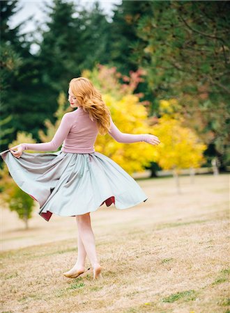 Young female dancer twirling and  lifting skirt in park Stock Photo - Premium Royalty-Free, Code: 614-08126669
