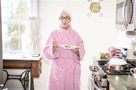 serious older woman looking at camera - Senior woman standing in kitchen holding plate of food Stock Photo - Premium Royalty-Free, Code: 614-08126856