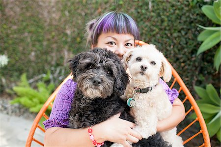 Mid adult woman sitting outdoors, hugging two dogs Stock Photo - Premium Royalty-Free, Code: 614-08148318