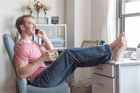 people feet up - Mid adult man with feet up on desk chatting on smartphone Stock Photo - Premium Royalty-Free, Code: 614-08148571