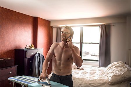 simsearch:614-03982063,k - Mid adult man wearing boxer shorts chatting on smartphone whilst ironing Photographie de stock - Premium Libres de Droits, Code: 614-08148572