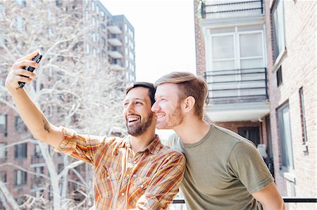 simsearch:614-08148673,k - Male couple standing on balcony, taking self portrait, using smartphone Stock Photo - Premium Royalty-Free, Code: 614-08148684