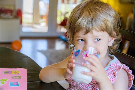 Portrait of cute young girl drinking glass of milk at kitchen table Stock Photo - Premium Royalty-Free, Code: 614-08148702