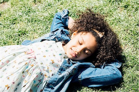 sunning - High angle view of girl lying on back on grass, hands behind head, eyes closed Stock Photo - Premium Royalty-Free, Code: 614-08201842