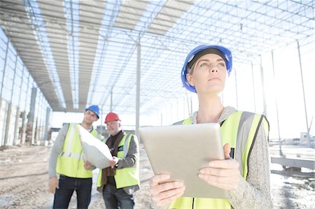 Female surveyor looking up from digital tablet on construction site Stock Photo - Premium Royalty-Free, Code: 614-08202152