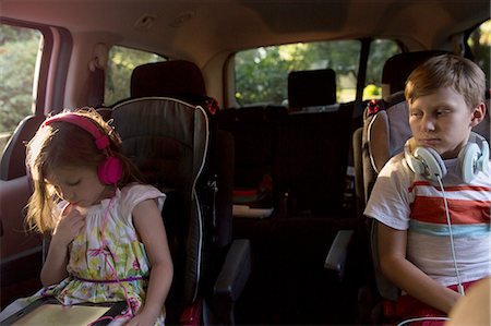 family inside car - Boy watching younger sister using digital tablet in car back seat Stock Photo - Premium Royalty-Free, Code: 614-08219857