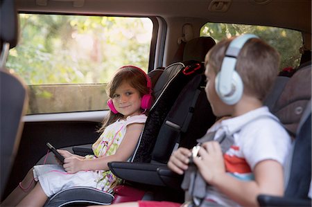 family inside car - Boy and younger sister wearing headphones and using digital tablet in car back seat Stock Photo - Premium Royalty-Free, Code: 614-08219864