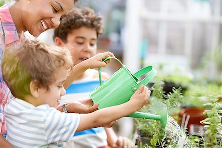 family indoors summer - Mid adult woman and two sons watering plants in greenhouse Stock Photo - Premium Royalty-Free, Code: 614-08270224