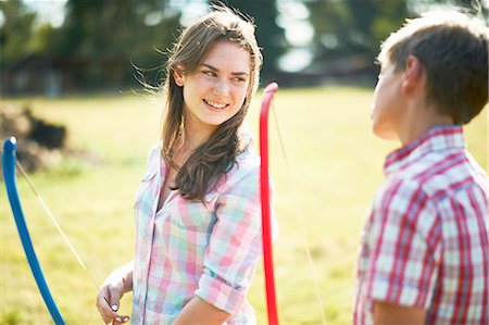 Teenage girl talking to brother whilst practicing archery Stock Photo - Premium Royalty-Free, Code: 614-08270384