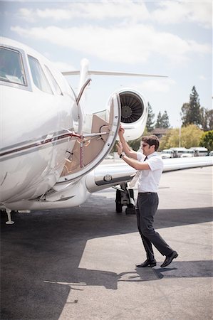 Male private jet pilot closing plane door at airport Stock Photo - Premium Royalty-Free, Code: 614-08307863