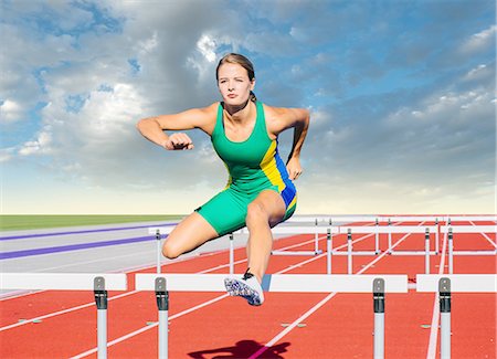 Runner jumping over hurdle on track Stock Photo - Premium Royalty-Free, Code: 614-08307957