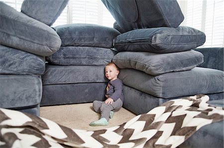 Boy leaning against pile of cushions in living room Foto de stock - Sin royalties Premium, Código: 614-08307992