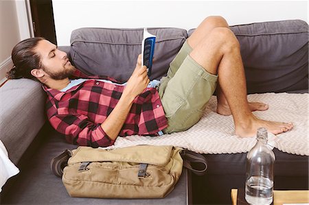 simsearch:6113-07731119,k - Young man relaxing on sofa, reading book Stock Photo - Premium Royalty-Free, Code: 614-08329392