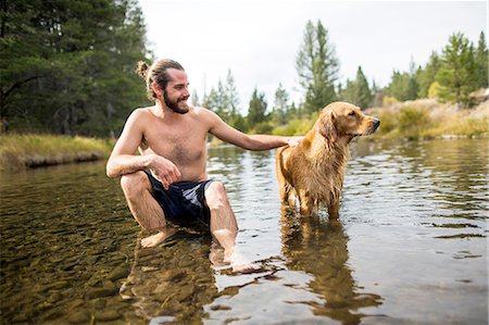 sit man dog - Young man sitting in river petting dog, Lake Tahoe, Nevada, USA Stock Photo - Premium Royalty-Free, Code: 614-08329436