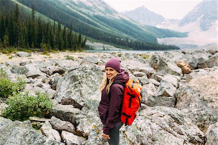 simsearch:614-07240106,k - Side view of mid adult woman on rocky landscape carrying backpack looking at camera smiling, Moraine Lake, Banff National Park, Alberta Canada Stock Photo - Premium Royalty-Free, Code: 614-08383512