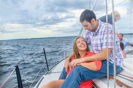 simsearch:614-06043438,k - Young woman sitting between young mans legs on sailboat, face to face smiling Photographie de stock - Premium Libres de Droits, Code: 614-08383523