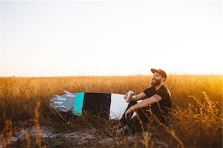 Male surfer drinking beer in field of long grass at sunset, San Luis Obispo, California, USA Photographie de stock - Premium Libres de Droits, Code: 614-08383698